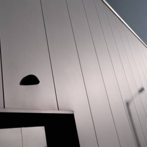 Street light's shadow cast upon aluminium cladding of a warehouse, adjacent to a doorway.  Belfast, Northern Ireland.